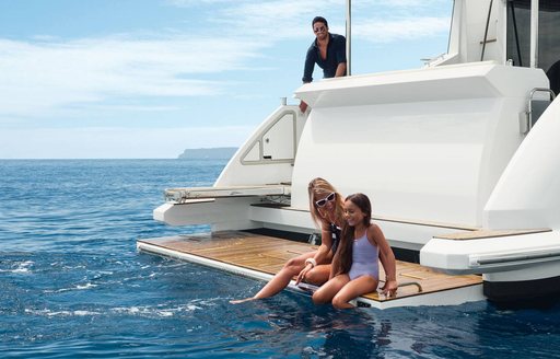 family relax on swim platform of luxury crewed yacht