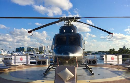 Helicopter on helipad at Fort lauderdale boat show with superyachts in background