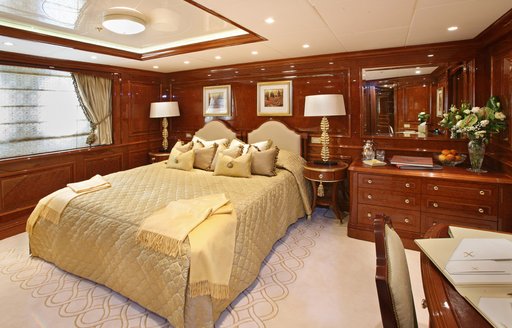 Main suite of luxury Benetti yacht St David, with large bed and warm wood accents