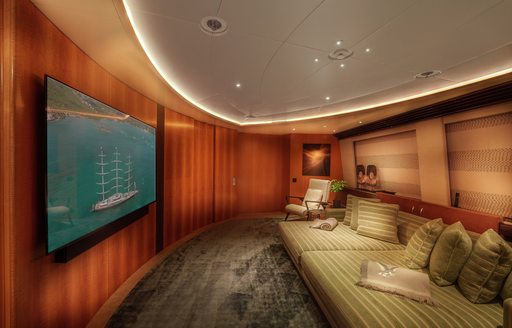 Cinema room onboard sailing yacht charter MALTESE FALCON, large wall-mounted screen facing a green seating area