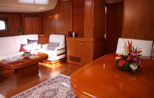 sofa and armchair sit opposite dining table in salon of charter yacht La Forza Del Destino 
