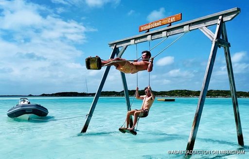 Pair of men swinging on sea swings while standing 