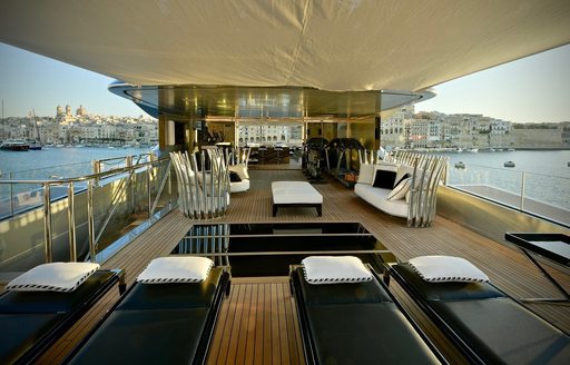 Overview of the sun deck onboard charter yacht SARASTAR, with black sunloungers in the foreground 