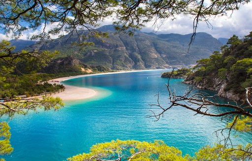 bright blue beautiful lagoon in turkey, white beach and pine forests surrounding
