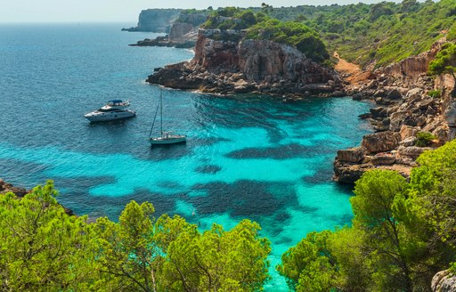 two charter yachts at anchor in a quiet cove of mallorca in Spain 