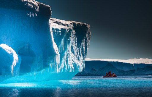 couple of people on a boat looking at the icy landscapes in Antarctica