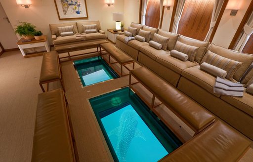 Interior seating area with glass panels in the floor onboard charter yacht SURI