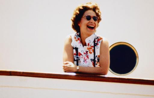 Queen Elizabeth with sunglasses on laughing onboard her Royal Yacht Britannia