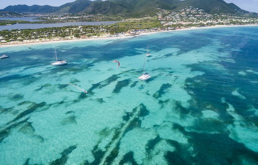 Aerial view of clear blue sea in the Caribbean, with some yachts sprinkled across the water