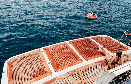 woman sits on swim platform of luxury yacht panthours