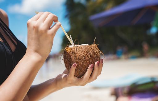 Womans hands hold coconut drink on beach in the Caribbean