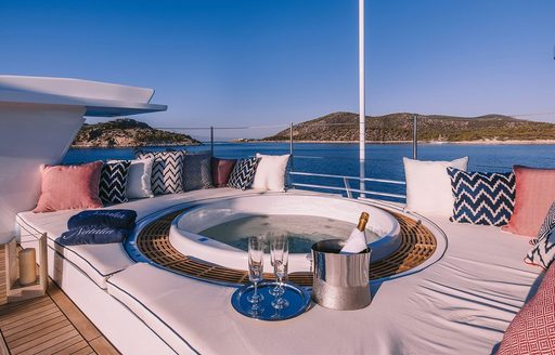 Overview of the on-deck Jacuzzi onboard charter yacht NATALIA V, central Jacuzzi surrounded by sunpads and views of the sea in the background