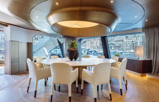 Interior dining area with circular white table and matching seats onboard boat charter THIS IS IT