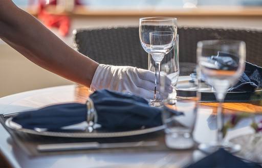 crew with white glove prepares a dinner table on a luxury superyacht 