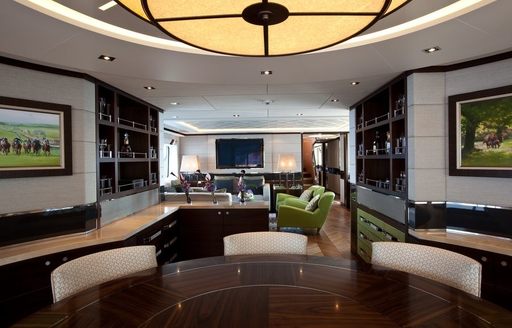 sophisticated main salon on board superyacht AURELIA  with white walls, dark wood furniture and lime green sofa