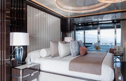 Overview of the master cabin onboard Charter yacht RESILIENCE. Central berth facing starboard with full height window in the background