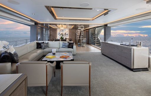 Main salon onboard charter yacht ENTREPRENEUR, spacious lounge area to port side and wide reaching windows on either side.