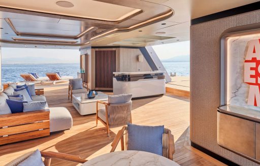 Overview of the open beach club onboard charter yacht MALIA, with ample seating arrangements and dual views of the sea.