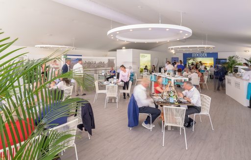 People eating at separate dining tables in the Upper Deck Lounge and Bar at the Monaco Yacht Show