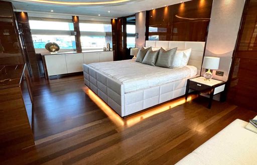 Master cabin onboard Charter yacht LE VERSEAU, central berth facing port with large windows in the background.