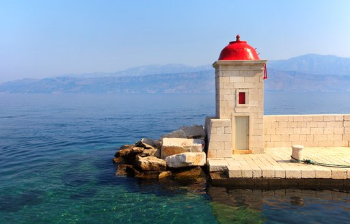 red domed chapel on small island in croatia, mountains in background