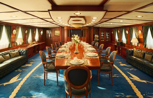 Interior dining area onboard charter yacht SEAGULL II, long table and blue upholstered chairs 