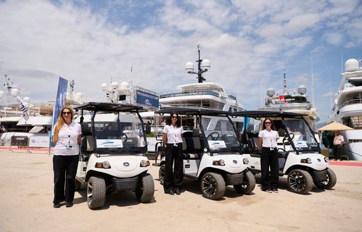 Three carts and drivers standing on the quayside at MEDYS, with private yacht charters in the background