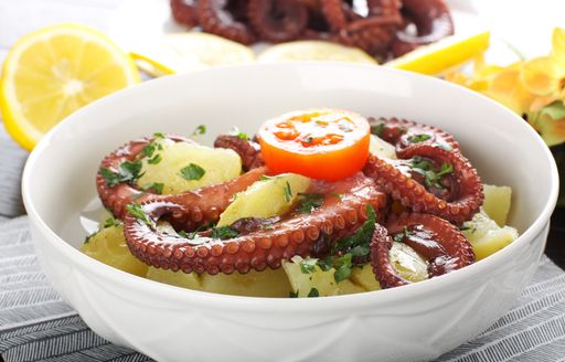 A white bowl containing potatoes and tomatoes with octopus tentacles from Sardinia