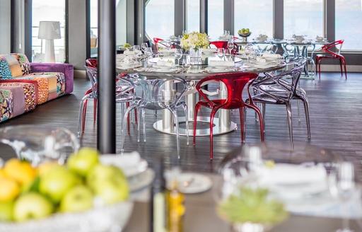 dining salon with colourful chairs and full-length windows aboard motor yacht SALUZI