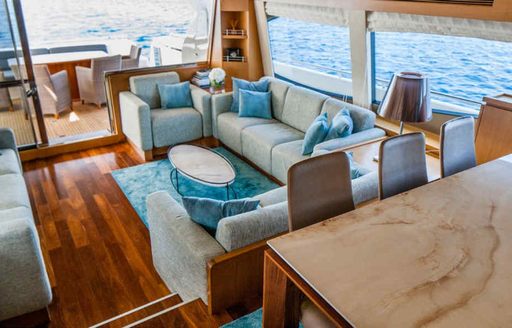 Inside the main salon onboard charter yacht ORLANDO L, with dining set up forward and a plush lounge area in the background