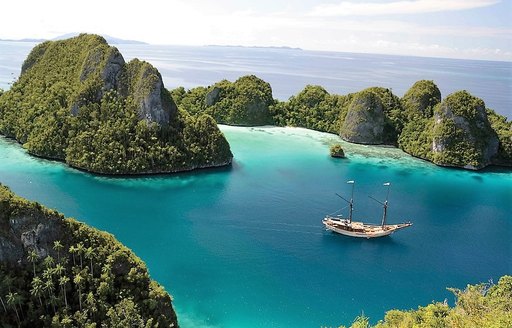 A luxury gulet cruises between green mountains in South East Asia