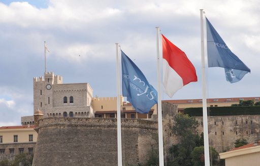 three Monaco Yacht Show flags flutter in the wind in Monaco