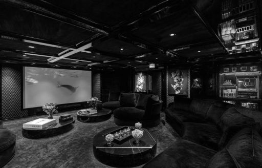 Indoor cinema onboard luxury charter yacht EMIR, plush seating around the room with a large wall-mounted screen opposite