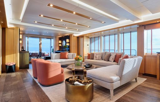 Main salon onboard charter yacht MAKANI II, spacious lounge area with plush cream and coral seating