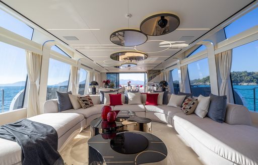 Main salon onboard charter yacht N1, U-shaped white plush seating with extensive glazing
