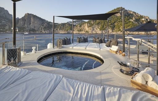 Overview of the aft deck onboard charter yacht Silver Angel, with a central Jacuzzi surrounded by sun pads and views of the sea