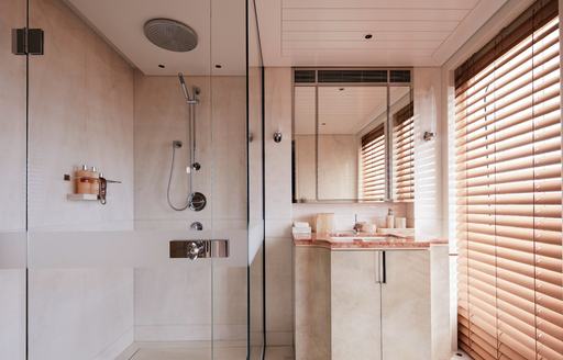 neutral pastel themed bathroom with waterfall shower head and marble detailing inside motor yacht JOY