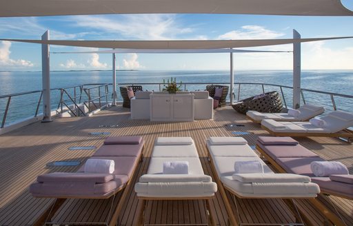 sun pads with bar beyond and calm seas on sun deck of charter yacht dream