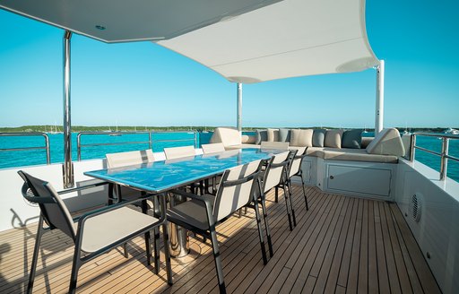 Exterior dining set up on the flybridge of charter yacht ONLY NOW, surrounded by views of the sea