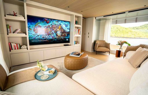 Interior lounge area onboard charter yacht STELLAMAR, with plush seating and a huge wall-mounted flatscreen TV