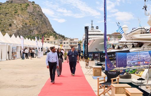 Industry professionals walking on red carpet at MEDYS, looking at superyacht charters