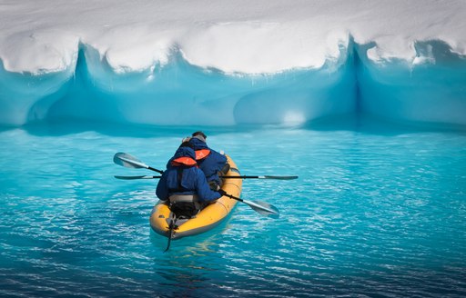 Kayakers paddle towards glacier in Antartica