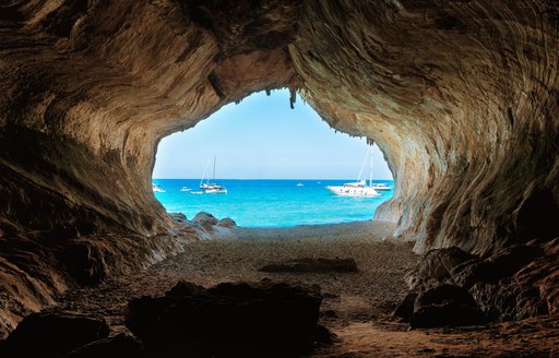 A view through a cave out to turquoise waters in Sardinia, Italy