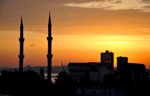 Two minarets silhouetted against an amber sky at dusk in Turkey