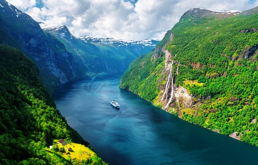 a superyacht crusing down a fjord in norway