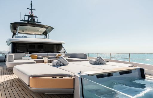 Exterior deck space onboard charter yacht LUZ DE MAR, Jacuzzi in the foreground with large sunpads and seating aft.
