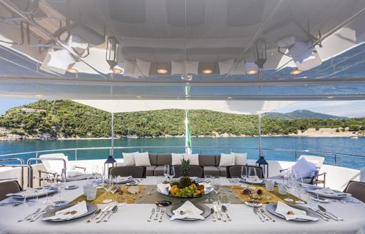 Large dining table on motor yacht Ferdy with a view of the sea and greenery