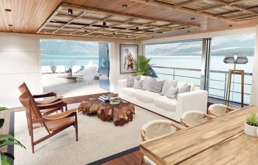 Overview of the main salon onboard charter yacht KB6, with dining area in the foreground and a lounge with exterior access aft. Surrounded by large full height windows.