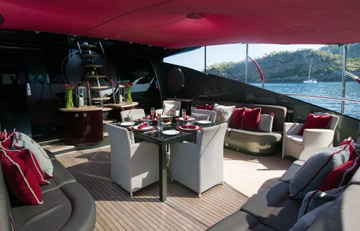 Alfresco dining and seating area on superyacht ASCARI I with red Bimini shading above