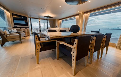 Dining area onboard luxury yacht rental SEA-RENITY, long table with black upholstered chairs